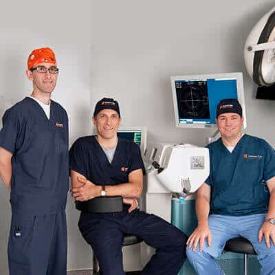 cataract surgeons posing next to their equipment